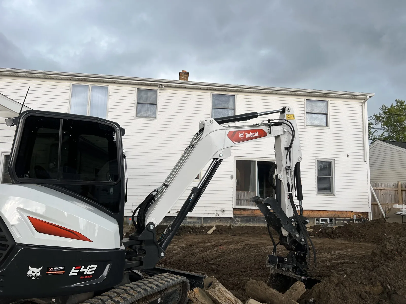 Excavator preparing the ground beside a home