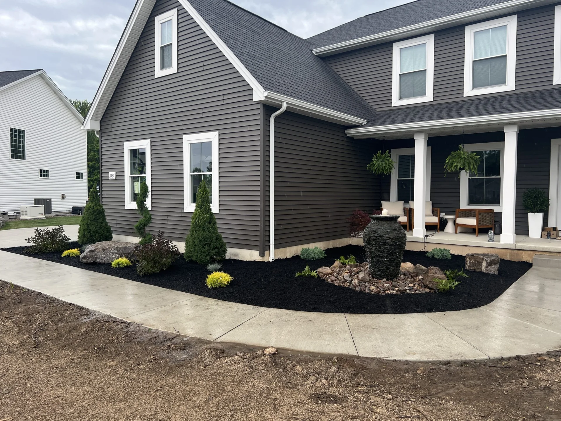 Mulched garden beds and shrubs along the front of a home