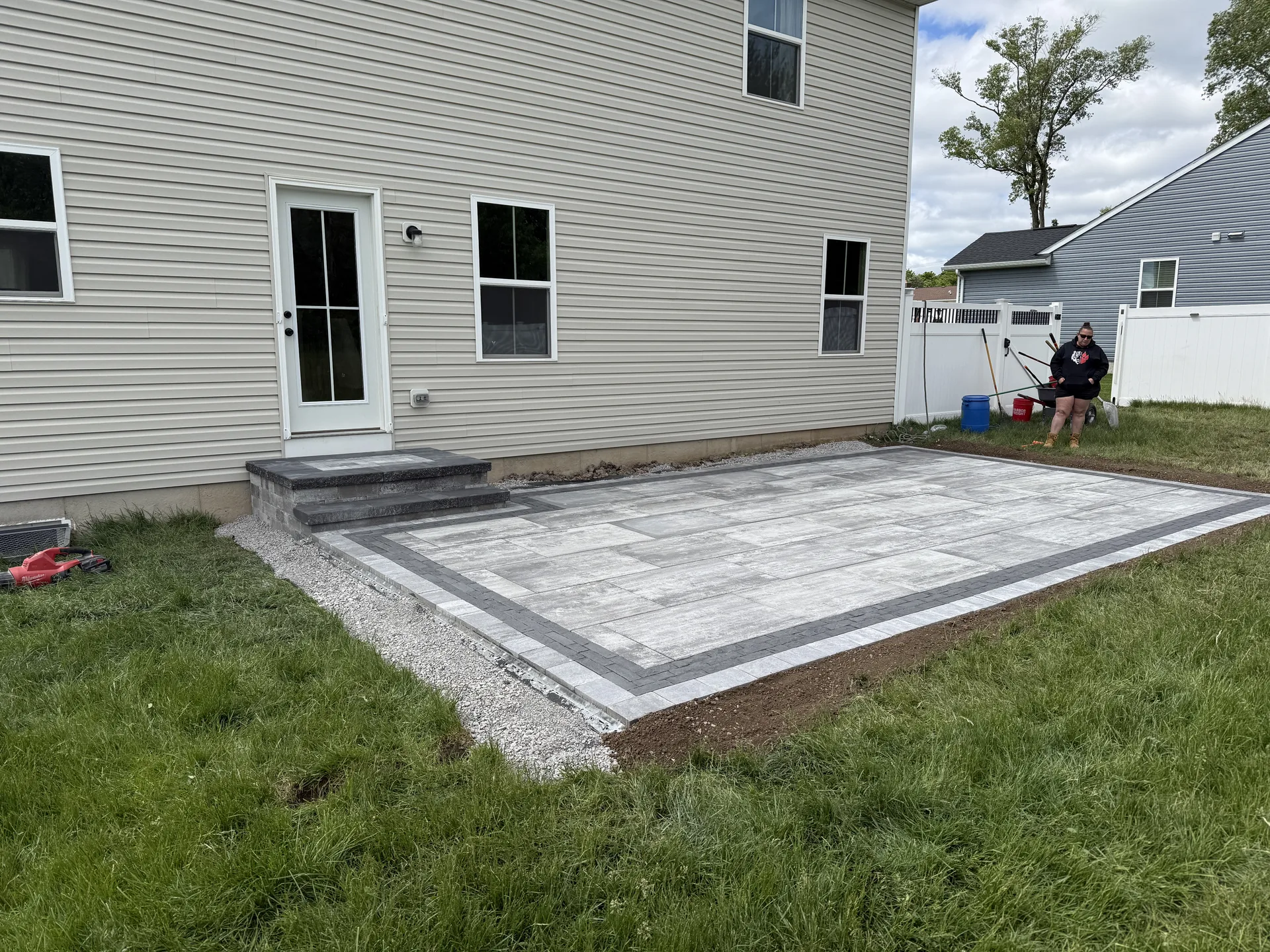 Rectangular paver patio with a contrasting border beside a home