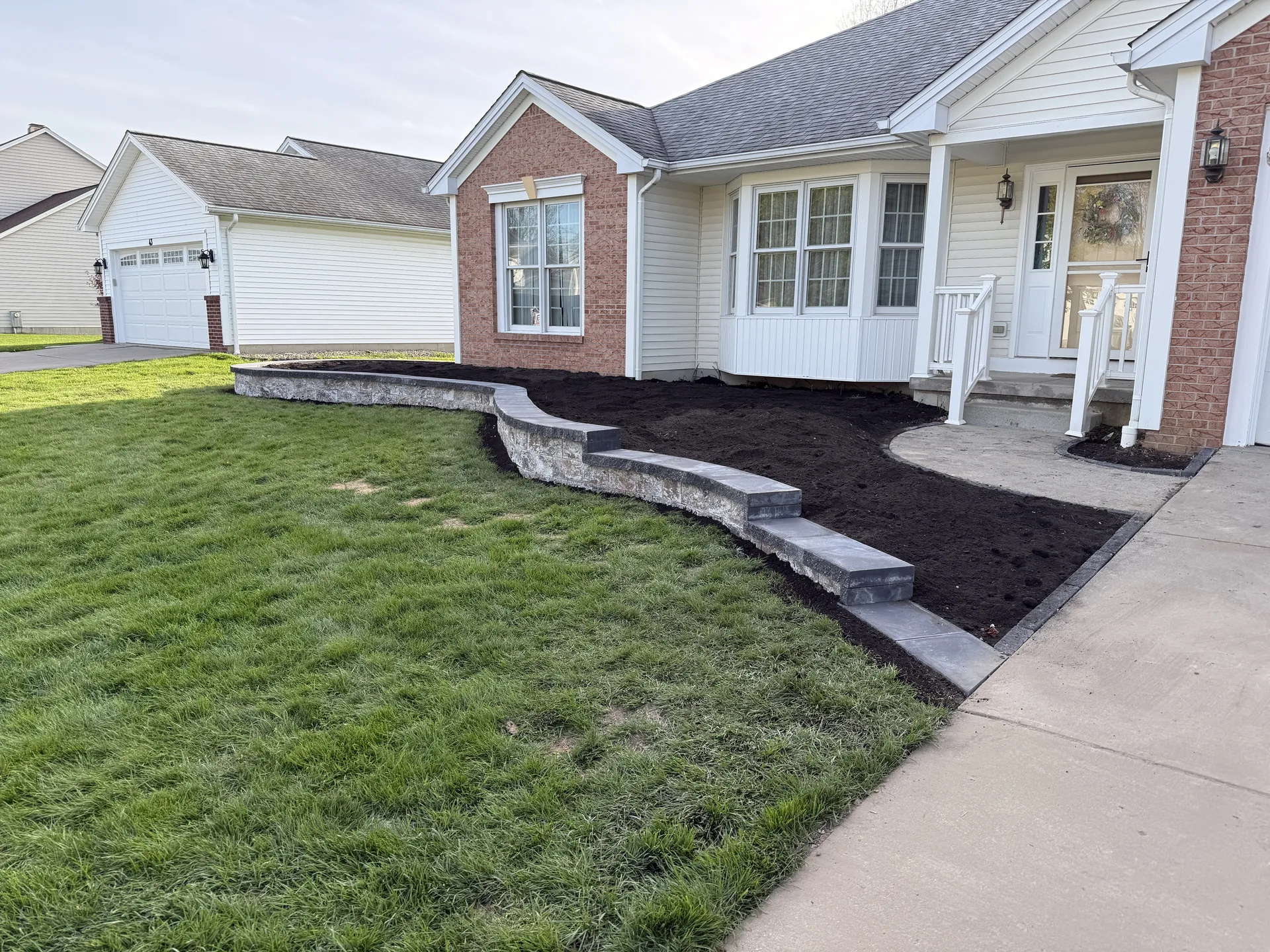 Curved stone border around a freshly mulched front garden