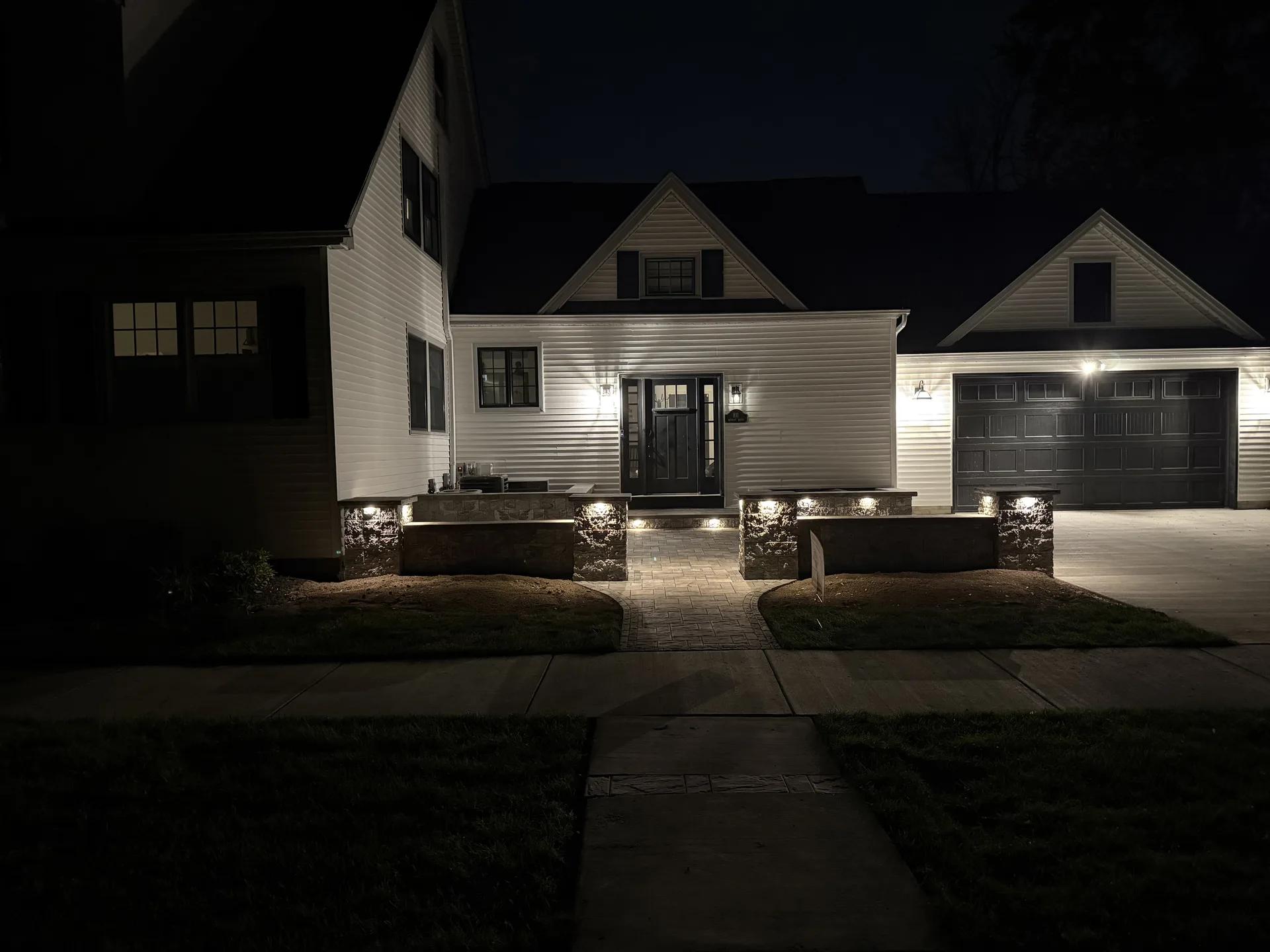 House and stone entry courtyard illuminated by landscape lighting at night