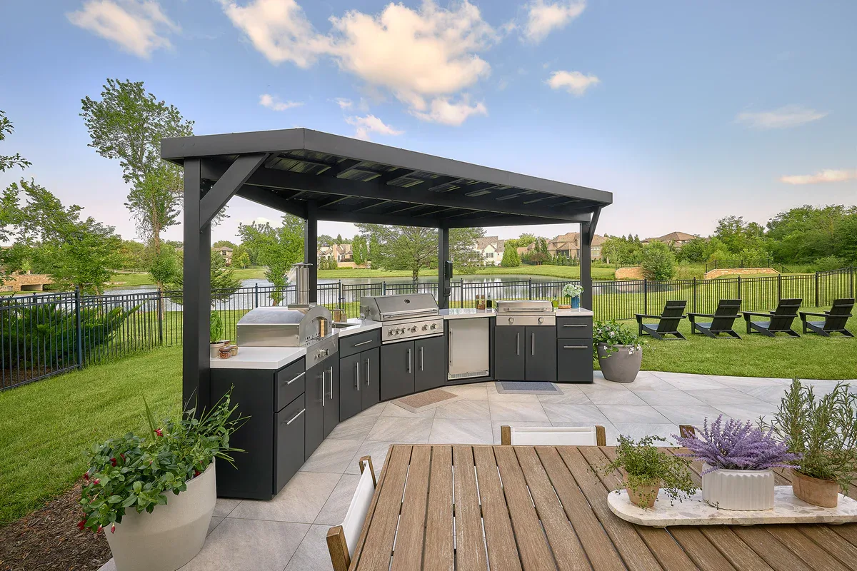 Covered outdoor kitchen and dining area overlooking a lawn