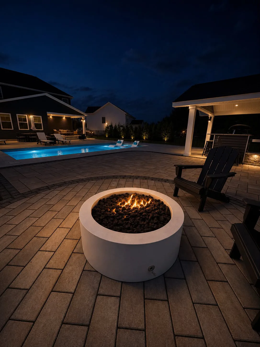 Glowing fire bowl beside an illuminated swimming pool at night